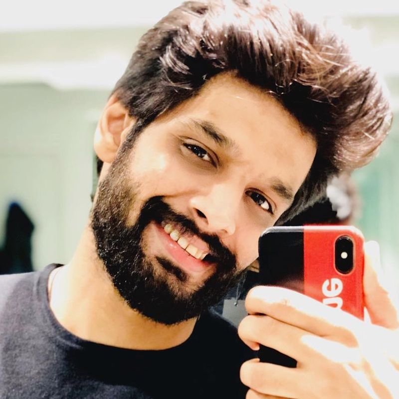 رجل بتسريحة "بومبادور" عفوية (غير مرتبة) ولحية كاملة يلتقط صورة سيلفي أمام المرآة