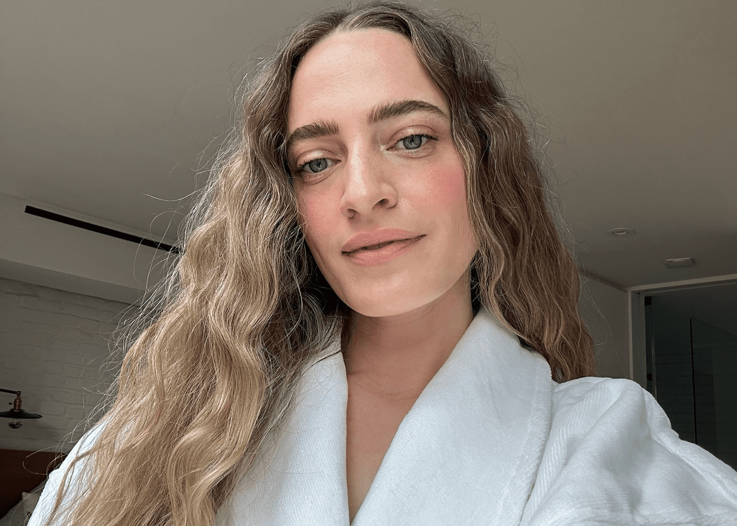 woman with blonde wavy hair posing in hotel robe