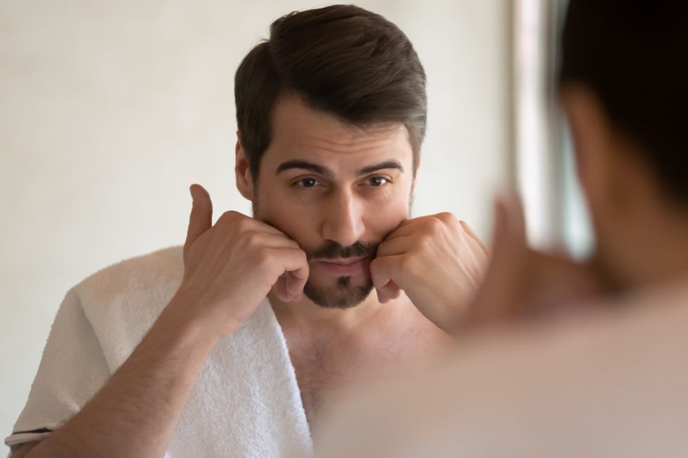 رجل ينظر في المرآة بعد تهذيب شاربه